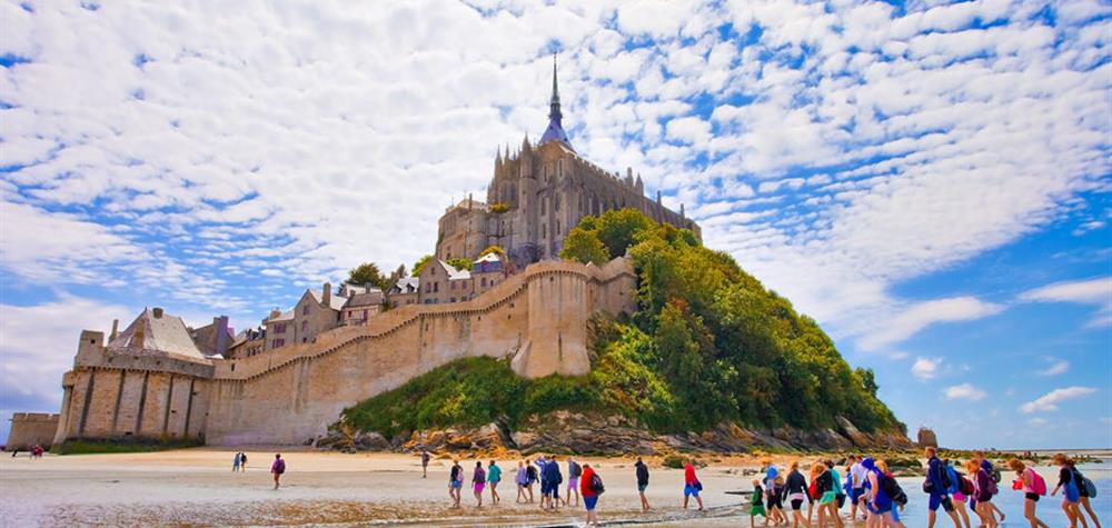 Groupe de touristes traversant les sables vers le Mont-Saint-Michel