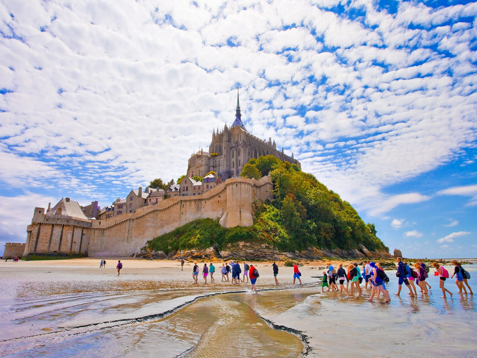 Groupe de touristes traversant les sables vers le Mont-Saint-Michel