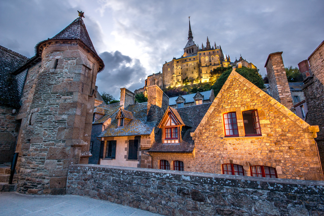 Mont-Saint-Michel illuminé au crépuscule avec les bâtiments en premier plan